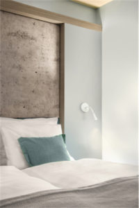 Luminaire mural moderne ETON Kuzco WH18901-WH dans la chambre à coucher au mur près du lit