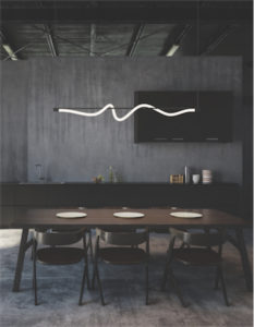 Luminaire suspendu moderne CURSIVE Kuzco LP95354 allumé au-dessus de la table de salle à manger en bois avec mur de béton